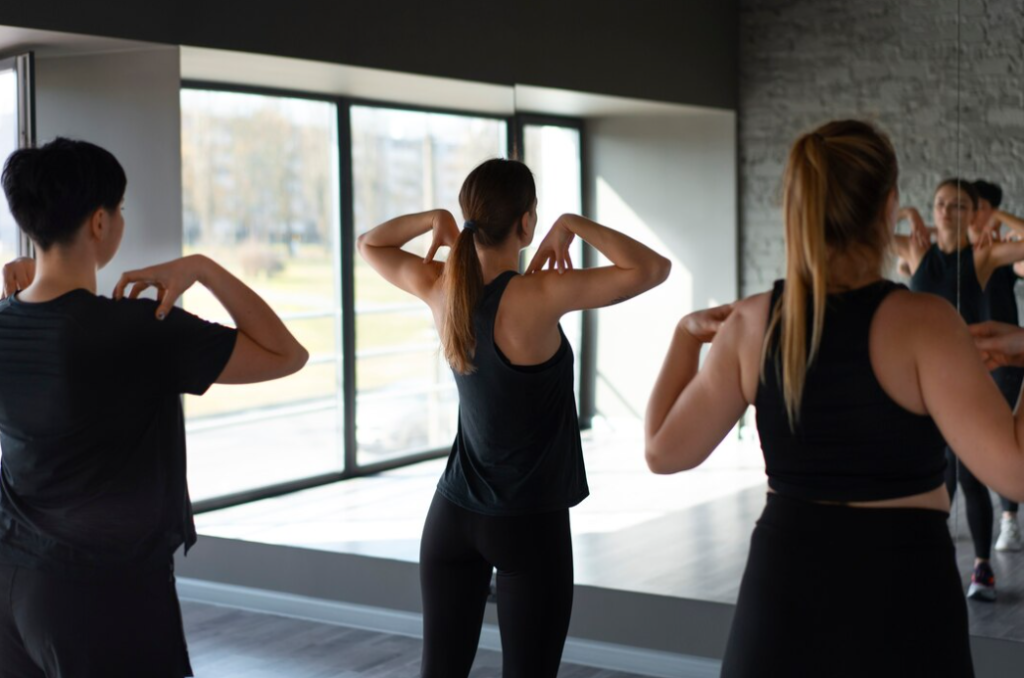 A group of individuals participating in a fitness class, with focus on their mirrored poses