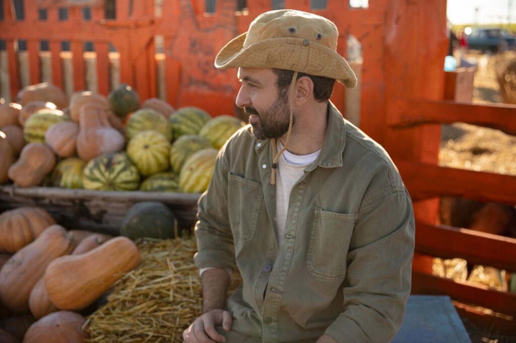 Male farmer with the harvest of pumpkins and watermelons at his farm