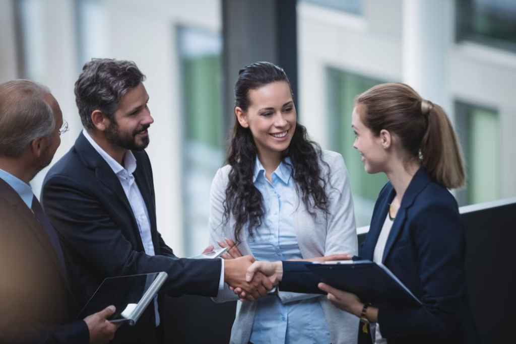 people in formal attire exchange a firm handshake, and woman between them looks at them