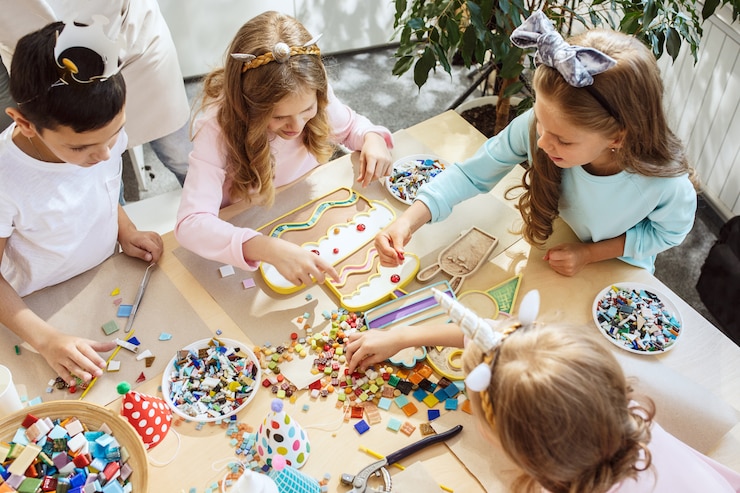little girls sitting around the table and making decorations for the party